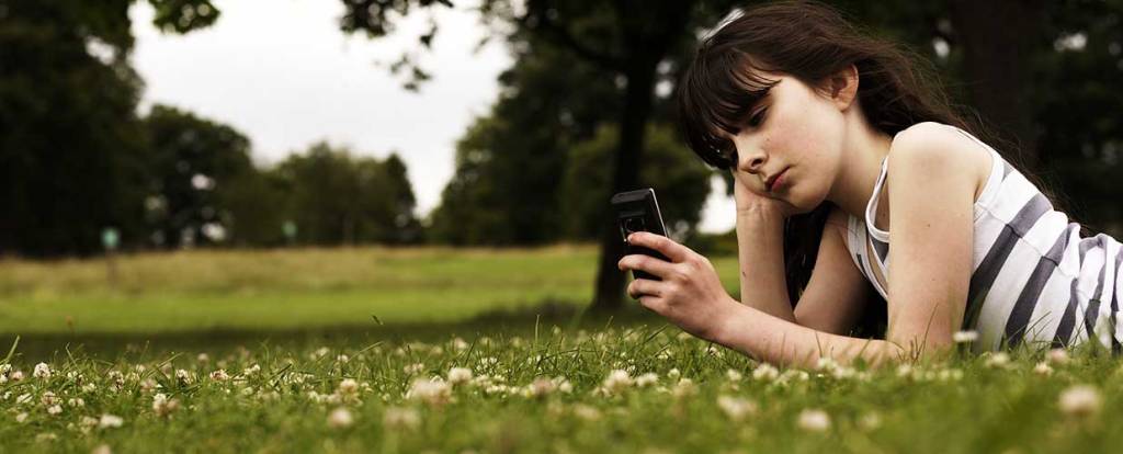 Girl laying on grass with cell phone
